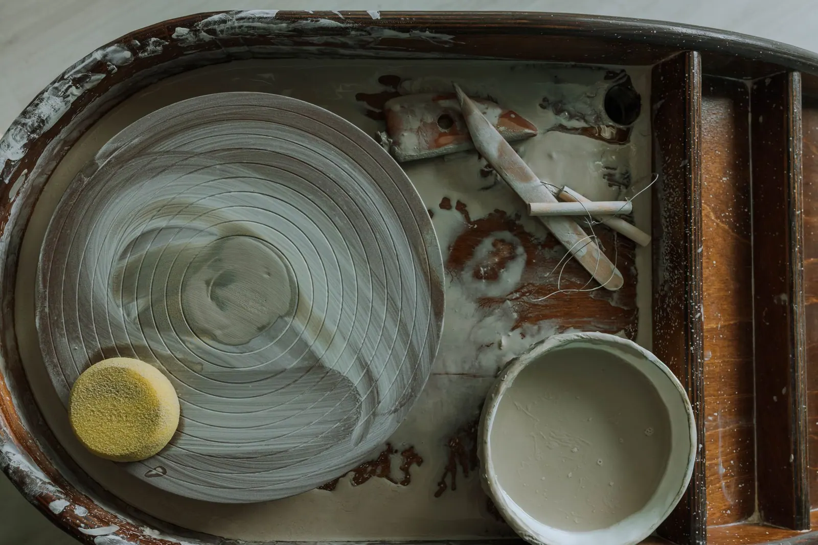 Detailed view of a pottery wheel and clay tools in an artisan's workspace, showing creative process. Pricing supplies around the mistakes that waste them