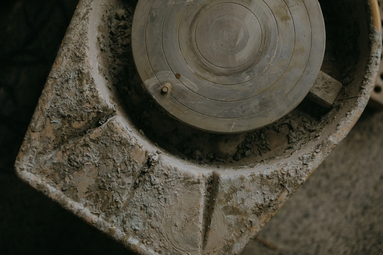A close-up of a rustic clay-covered pottery wheel, showcasing texture and artisanal craft. Beginner pottery wheels storage: a dry, dust-free routine