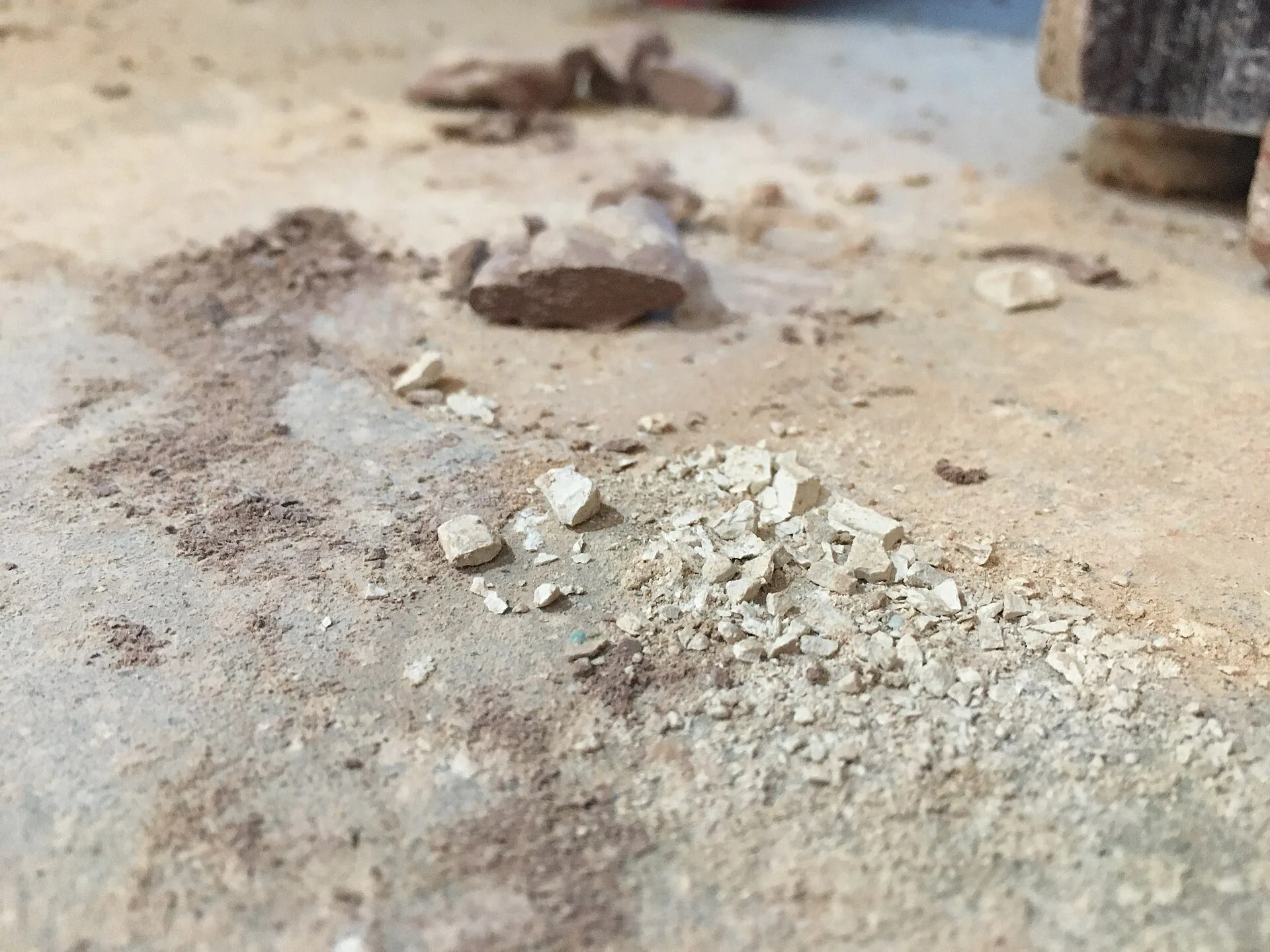 Different size grains of clay dust on the floor of a ceramics studio. Small ceramics projects expert tips: recycle clay, control dust