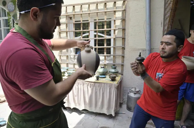 This image shows two craftsmen working together with handmade ceramic vessels. The scene documents Rishton ceramic craftsmanship. It documents cultural heritage in Fergana Region. What working makers wish they knew about home kilns